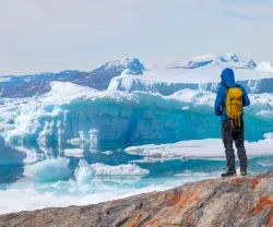 Um homem, explorador, olha para um icebergue no Ártico. Crédito: Shutterstock