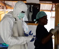 Imagem de uma enfermeira e de um médico vestidos com equipamentos de segurança durante um surto de Ébola em África. Belen B. Massieu/shutterstock