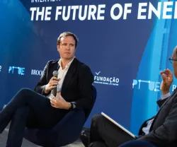 O jornalista britânico Ed Conway em palco, sentado, com um microfone na mão. O entrevistador de costas. Fundo azul com o texto "The Future of Energy". DR/FFMS