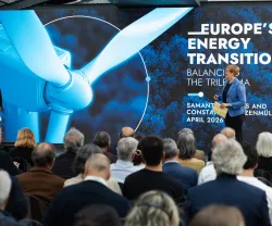 Uma plateia de costas a assistir à apresentação de duas mulheres, num palco. Texto "Europe's Energy Transition".