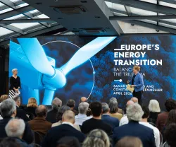 Uma plateia de costas a assistir à apresentação de duas mulheres, num palco. Texto "Europe's Energy Transition".