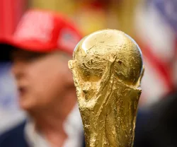 Imagem do troféu do Mundial 2026 em foco e, ao fundo, desfocado, Donald Trump. Créditos: shutterstock