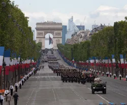 Desfile na avenida Champs-Elysees, em Paris, no dia da Bastilha. Soldados a desfilar e várias bandeiras do país.