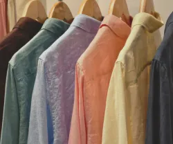 Imagem de várias camisas coloridas penduradas num cabide. Crédito: Shutterstock, com expansão de iamgem com recurso a IA.