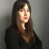 Imagem de uma mulher jovem, a psicóloga Ensaio Ludmila D. Nunes, sob um fundo neutro. D/R.