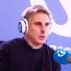 Retrato do professor João Canário, de fones na cabeça, a falar para um microfone.