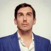Retrado do humorista Cláudio Almeida a olhar para cima.