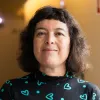 Retrato da psiquiatra Manuela Silva a sorrir. Fundo amarelo.