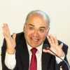 Retrato de um homem, o historiador José Eduardo Franco, a falar para um microfone e a gesticular.