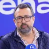 Retrato de um homem, sentado, a falar ao microfone, no estúdio da rádio Renascença.