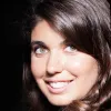 Imagem de uma mulher jovem, a jornalista Sara Capelo, sob um fundo escuro. Crédito: D/R