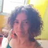 Imagem de uma mulher, com um top verde e brincos laranja.