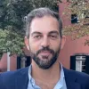 Imagem de um homem, com barba. Camisa e casaco azuis.