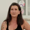 Retrato de uma mulher, vestida com um top preto e uns brincos dourados.