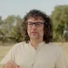 Retrato a cores de um homem, que usa óculos, e veste uma camisa clara. 