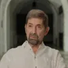 Retrato a cores de um homem, de cabelo e barba castanha, vestido com uma camisa branca.