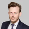 Retrato a cores de um homem de olhos azuis e cabelo castanho. Veste um fato azul. Fundo cinzento claro. Créditos:CNAS