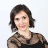 Retrato a cores de uma mulher a sorrir; tem cabelo escuro, uma blusa preta e um colar ao pescoço.