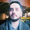 Retrato a cores de um homem com barba, a olhar para o lado, vestido com roupa de inverno.