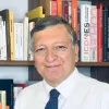 Retrato a cores de um homem, Durão Barroso, a sorrir, vestido com uma camisa branca. Uma estante de livros cobre o fundo. Créditos: EUI