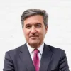 Retrato a cores de um homem, vestido com um fato preto e com uma gravata rosa com quadrados azuis. D/R
