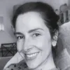 Retrato a preto e branco de uma mulher, a sorrir. Está de cabelo atado. D/R