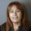 Retrato a cores de uma mulher de cabelo claro, vestida com uma camisola preta, sob um fundo cinzento.